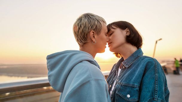 Young passionate lesbian couple kissing outdoors, Two women enjoying romantic moments together at sunrise - Фото, изображение