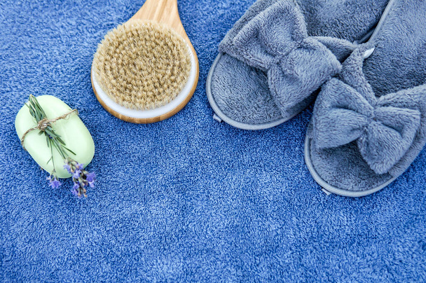 Spa day concept. Spa and wellness setting with bathrobe, brush, soap with lavender scent, slippers - Photo, image