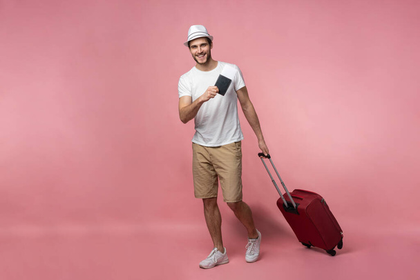 Man traveler with suitcase, passport and ticket on color background. - Photo, Image