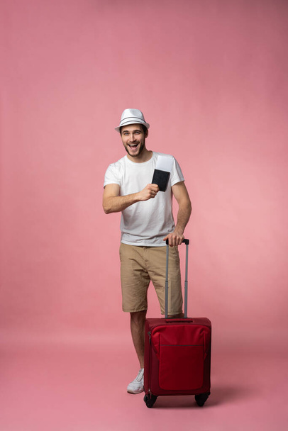 スーツケース、パスポート、チケットを持つ男性旅行者の色の背景. - 写真・画像