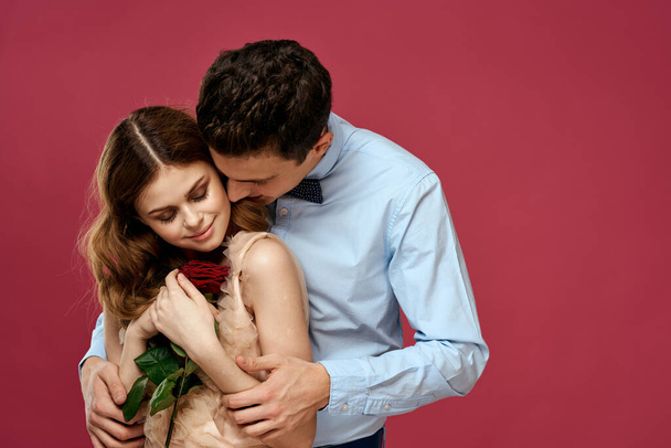 Любителі людей з трояндою в руках на рожевому ізольованому фоні обіймають емоції щасливі романтичні почуття
 - Фото, зображення