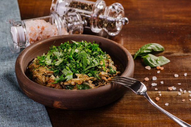 Dish with chopped meat with sauce and herbs on the wooden background - Foto, afbeelding