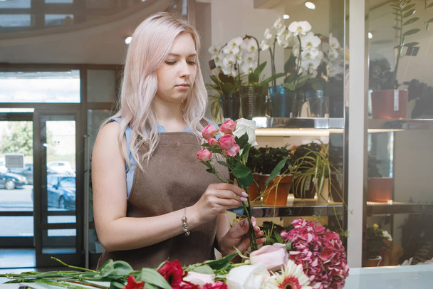 Блондинка квіткова жінка в фартусі на робочому місці квіткового магазину. Вибірковий фокус
. - Фото, зображення