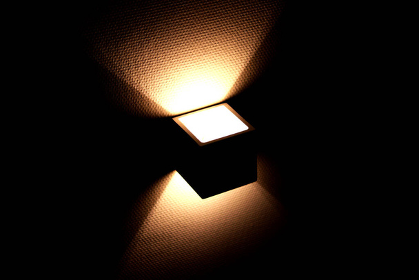 Moderne wandlamp in kubus vorm gloeiend 's nachts - Foto, afbeelding