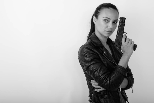 Stúdió lövés fiatal gyönyörű ázsiai nő visel bőrdzseki ellen fehér háttér fekete-fehér - Fotó, kép