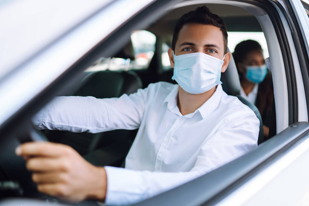 Man driving a car in protective sterile medical mask during an epidemic in quarantine city. Covid- 19. - Fotografie, Obrázek