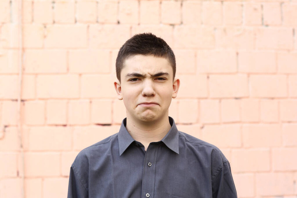 glücklich Teenager Junge Grimasse Augenzwinkern Nahaufnahme Porträt auf weißem Wandhintergrund - Foto, Bild
