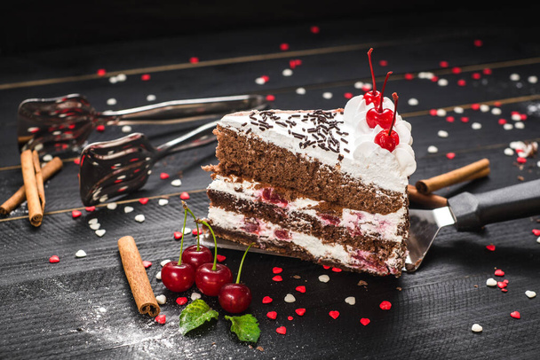 A piece of sweet cake with cherry with layers on black background - Foto, Imagem