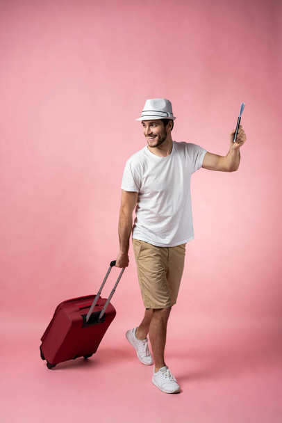 Man traveler with suitcase, passport and ticket on color background. - Foto, Imagem