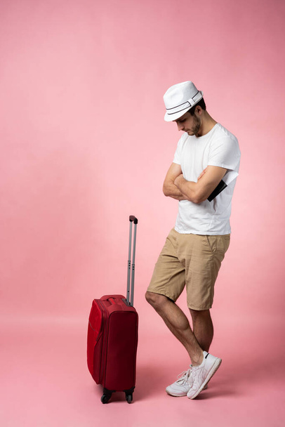 Man traveler with suitcase, passport and ticket on color background. - Foto, imagen