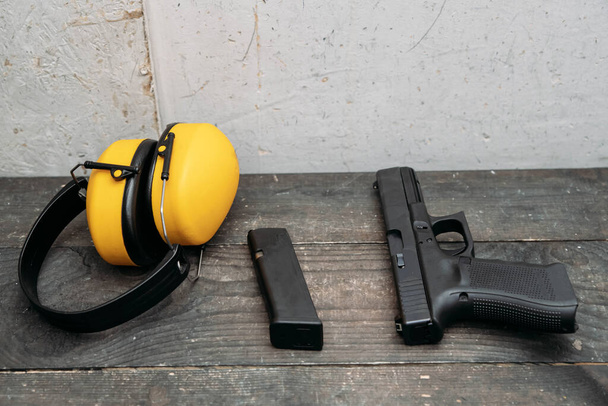 Schießstand. Ohrenschützer und Waffe liegen auf dem Tisch - Foto, Bild