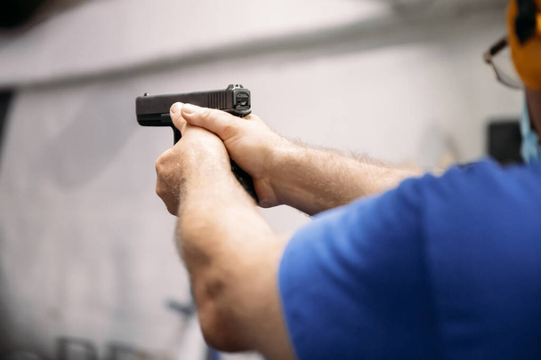 Жить в пандемии. Человек в медицинской маске нацелен на цель с пистолетом на стрельбище в условиях пандемии - Фото, изображение