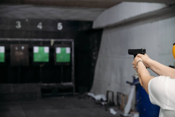 Shooting range. Rear view of woman shooting with gun in shooting range - Foto, immagini