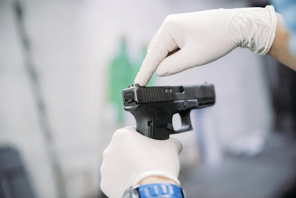 Žít v pandemii. Střelecký instruktor v rukavicích ukazující klientovi, jak používat zbraň na střelnici uprostřed pandemie - Fotografie, Obrázek