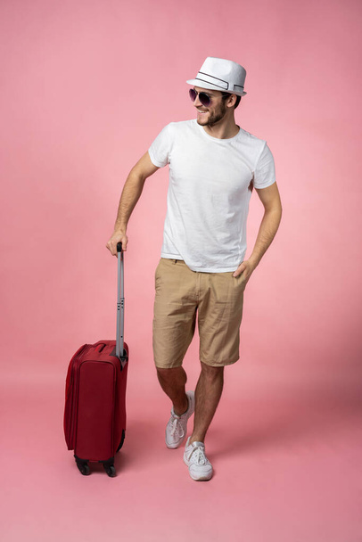 Man traveler with suitcase, passport and ticket on color background. - Фото, изображение