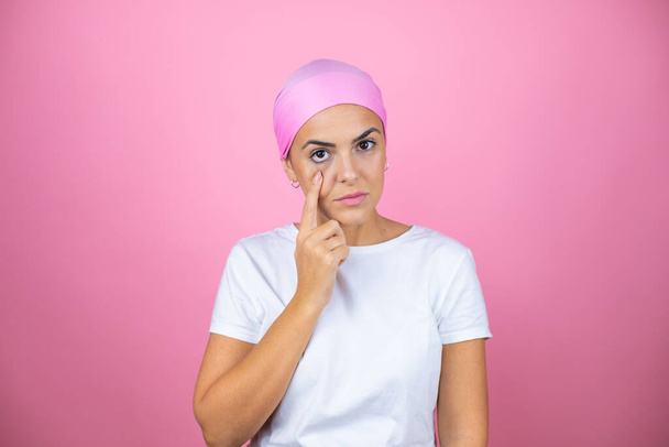 Young beautiful woman wearing pink headscarf over isolated pink background Pointing to the eye watching you gesture, suspicious expression - Valokuva, kuva