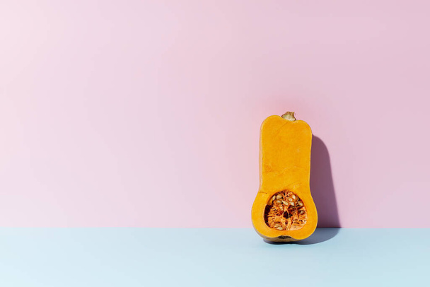 Halved butternut squash on pink and blue background. Healthy vegetarian ingredient. - Photo, image