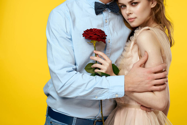 Enamored man and woman with red rose on yellow background cropped view close-up romance - Photo, Image