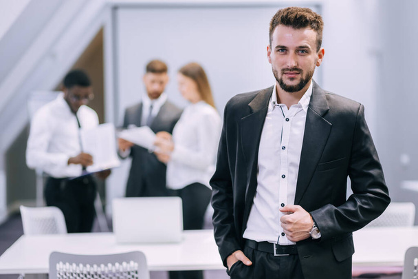 Çağdaş ofiste duran genç işadamı iş yerinde güven ve motivasyon gösteriyor, işyerinde poz veren mutlu milenyum Avrupalı erkek CEO 'su, liderlik, başarı konsepti. - Fotoğraf, Görsel