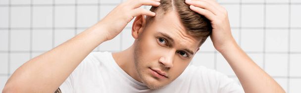 Worried young adult man checking hair in bathroom, banner - Фото, изображение