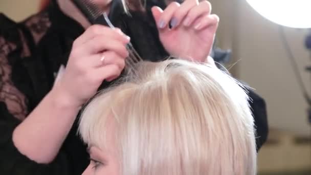 スタイリストは短い灰色の髪のためのヘアスタイルを行います。ビデオ - 映像、動画
