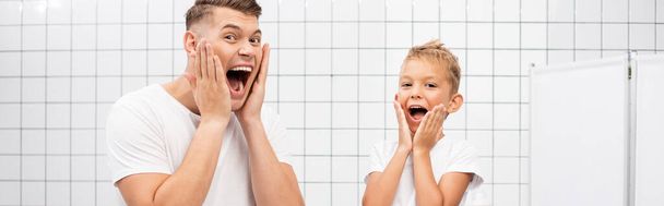 Šokovaný otec a syn křičí při dotyku tváře s rukama v koupelně, prapor - Fotografie, Obrázek