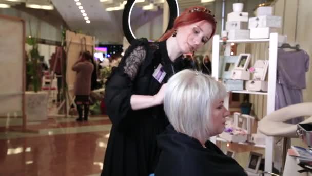Starší žena s krátkými šedými vlasy dělá styling v salonu krásy. Žena sedící před zrcadlem. Video - Záběry, video