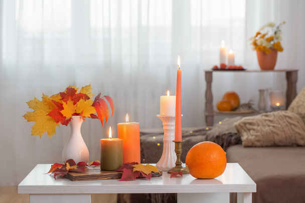 burning candles with autumn decor on white table at home - Φωτογραφία, εικόνα