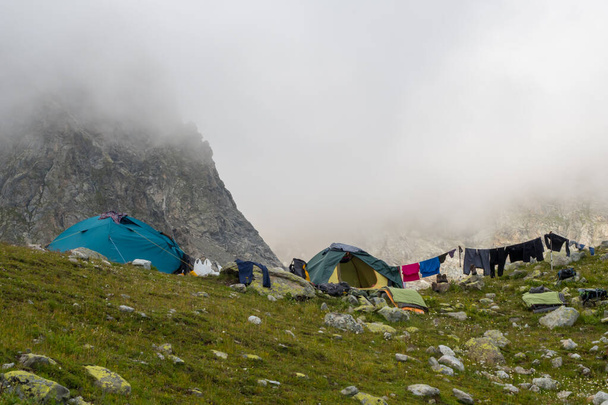 Tiendas de campaña en el campamento turístico. Ropa en el tendedero después de la lluvia en las montañas - Foto, imagen