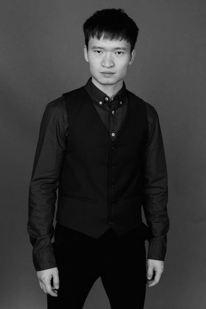 Estudio de un joven empresario chino sobre fondo gris en blanco y negro - Foto, Imagen