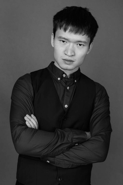 Studio zdjęcie młodego chińskiego biznesmena na szarym tle w czerni i bieli - Zdjęcie, obraz
