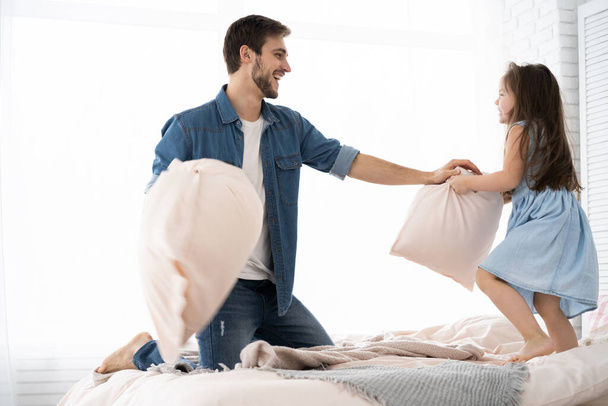 happy father and daughter playing pillow fight in bed at morning - Foto, immagini