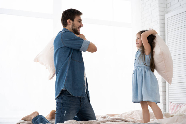 happy father and daughter playing pillow fight in bed at morning - Photo, Image