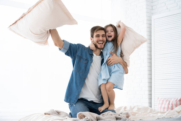 happy father and daughter playing pillow fight in bed at morning - Foto, afbeelding