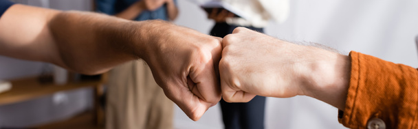 partial view of businessmen doing fist bump near colleagues on blurred background, banner - Photo, Image