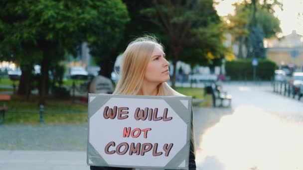 Spacer protestacyjny: kobieta trzymająca plakietkę ze słowami, których ludzie nie przestrzegają - Materiał filmowy, wideo