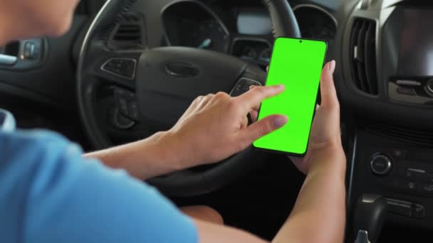 Женщина-водитель, использующая смартфон в машине. Chromakey смартфон с зеленым экраном. Автонавигация. Интернет-зависимость - Кадры, видео