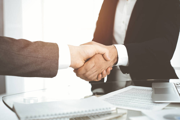 Unknown diverse business people are shaking hands finishing contract signing in sunny office, close-up. Business handshake concept - Photo, Image