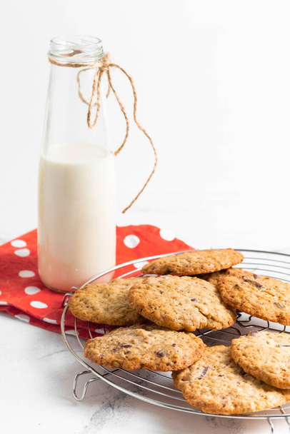Fresh oatmeal cookies and a glass bottle of milk on the white background - Фото, изображение