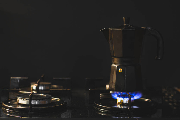Черный гейзер ретро кофеварка на газовой плите на черном фоне. Макроснимок приготовления кофе с копировальным местом - Фото, изображение