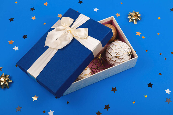 Μπλε κουτί γεμάτο από λευκές και χρυσές μπάλες χριστουγεννιάτικες διακοσμήσεις - Φωτογραφία, εικόνα