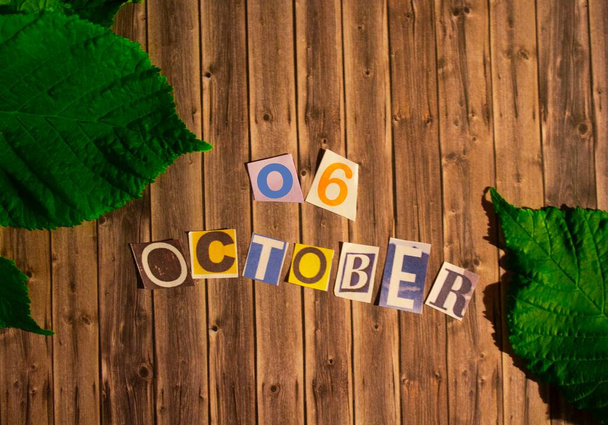 6. Oktober in bunten Buchstaben und Zahlen auf einem hölzernen Hintergrund. Herbst im Hintergrund. Oktober-Kalender - Foto, Bild