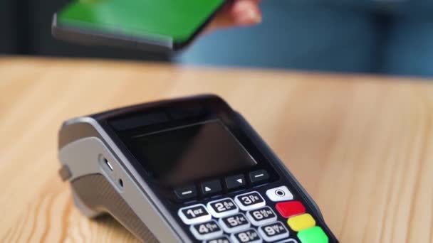 Contactless payment with smartphone with green mock-up screen. Wireless payment concept. Close-up, woman using smartphone cashless wallet NFC technology to pay order on bank terminal. - Footage, Video