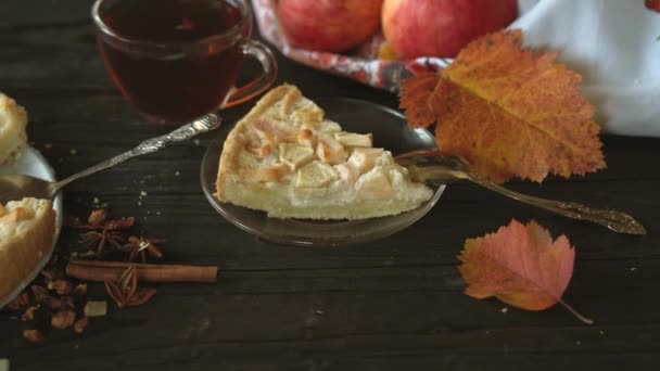 Кусок домашнего яблочного пирога Шарлотта из красных и желтых яблок. Натюрморт на тему осени, сбор яблок и домашней выпечки на темном деревянном столе. - Кадры, видео