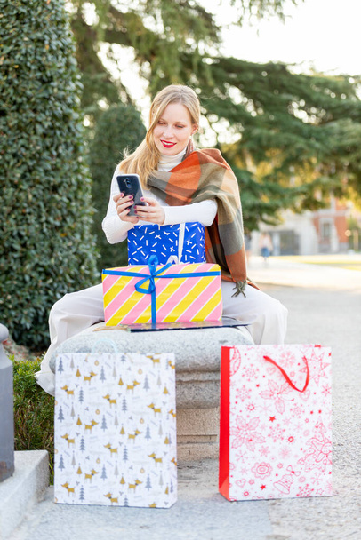 Karácsony jön az utcára, fiatal nő ajándékokkal, bevásárló táskák és karácsonyi dekorációk - Fotó, kép