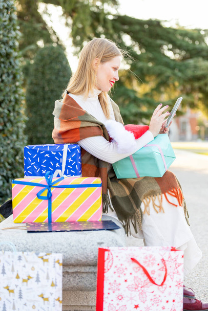 Kerstmis komt op straat, jonge vrouw met geschenken, boodschappentassen en kerstversieringen - Foto, afbeelding