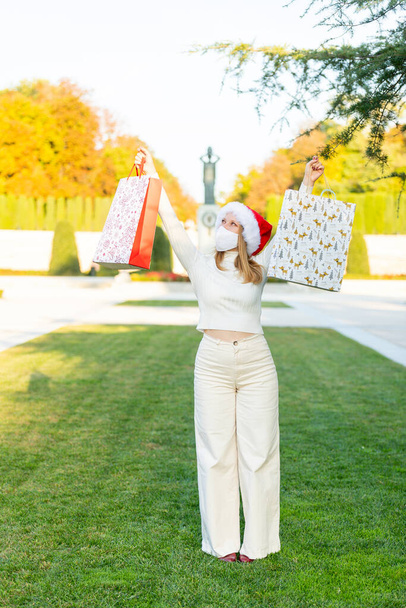 Karácsony jön az utcára, fiatal nő ajándékokkal, bevásárló táskák és karácsonyi dekorációk - Fotó, kép