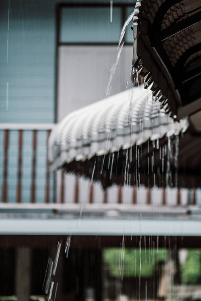 La gota de lluvia fluye desde un techo de la casa - Foto, Imagen