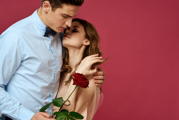 Любовники с розами в руках на розовом фоне обнимают эмоции счастья романтические чувства - Фото, изображение