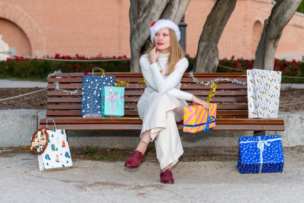 Christmas comes to the streets, young woman with gifts, shopping bags and Christmas decorations - Photo, Image